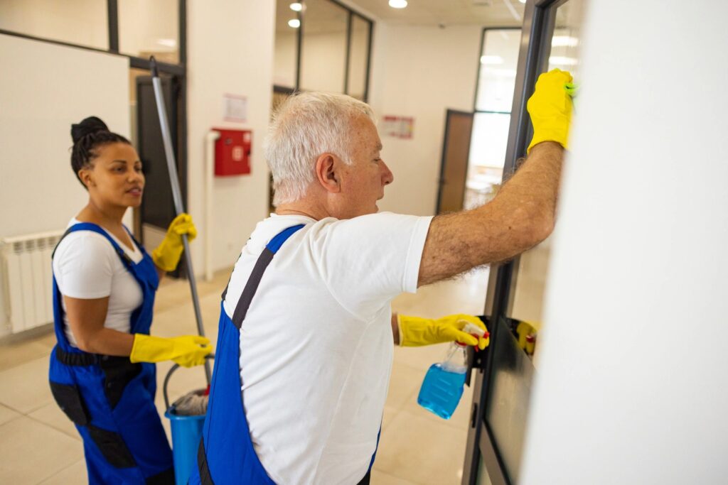 Professional cleaner wiping glass door